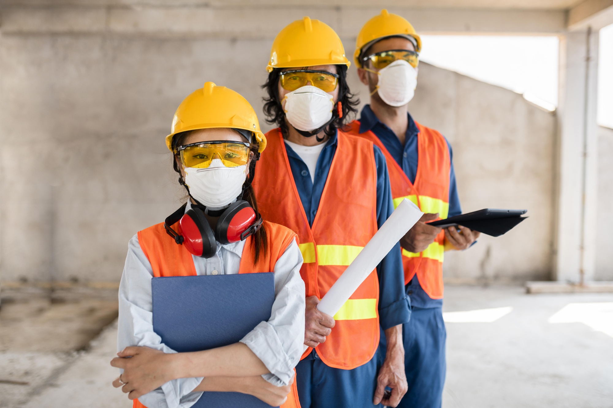 colleagues with safety equipment working with blueprints